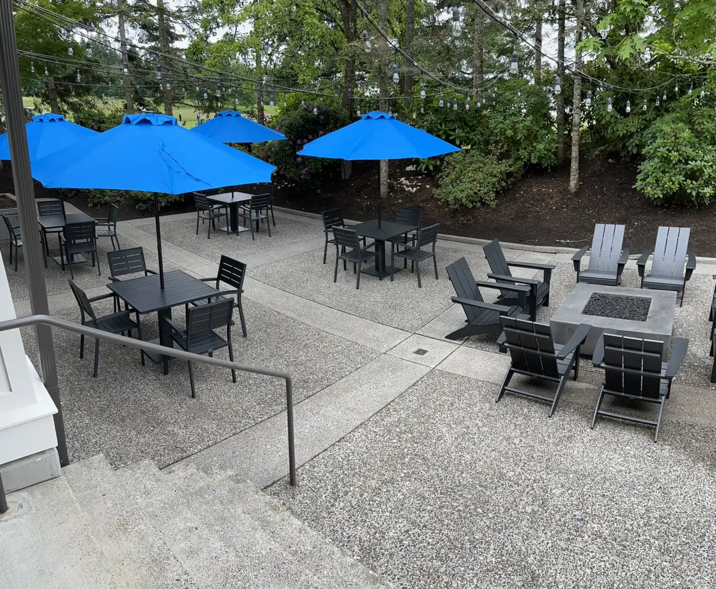 A clean aggregate concrete patio with tables and umbrellas after a wash