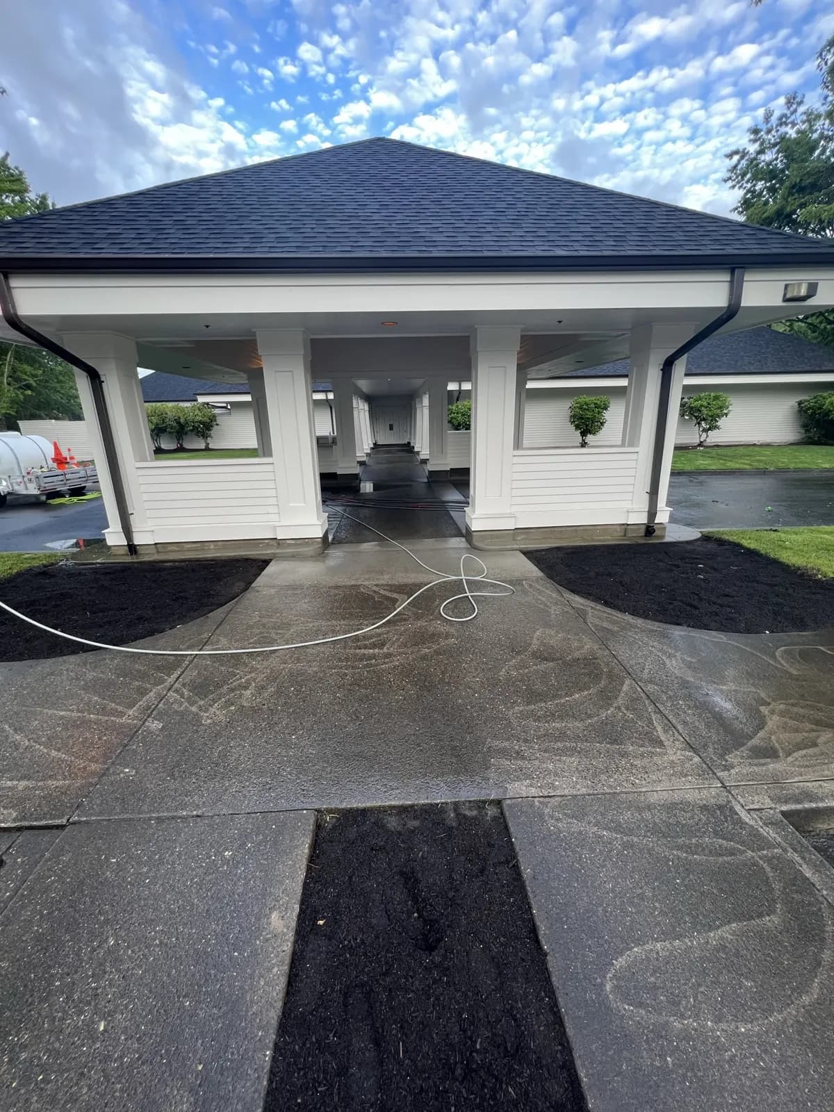 Clubhouse porte-cochère with freshly cleaned concrete and a hose still on the ground