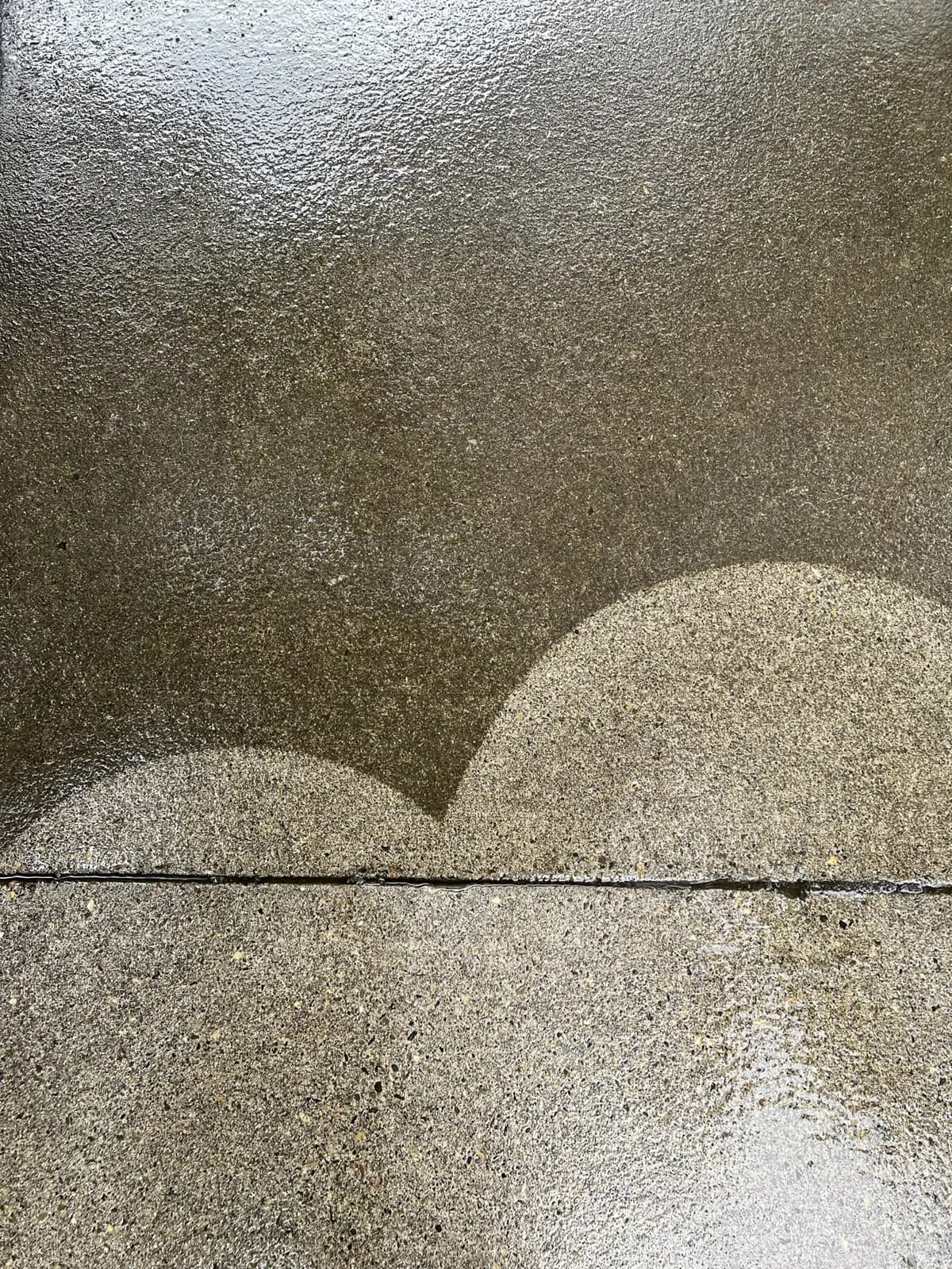 Close-up of concrete where two clean arcs meet untouched grime