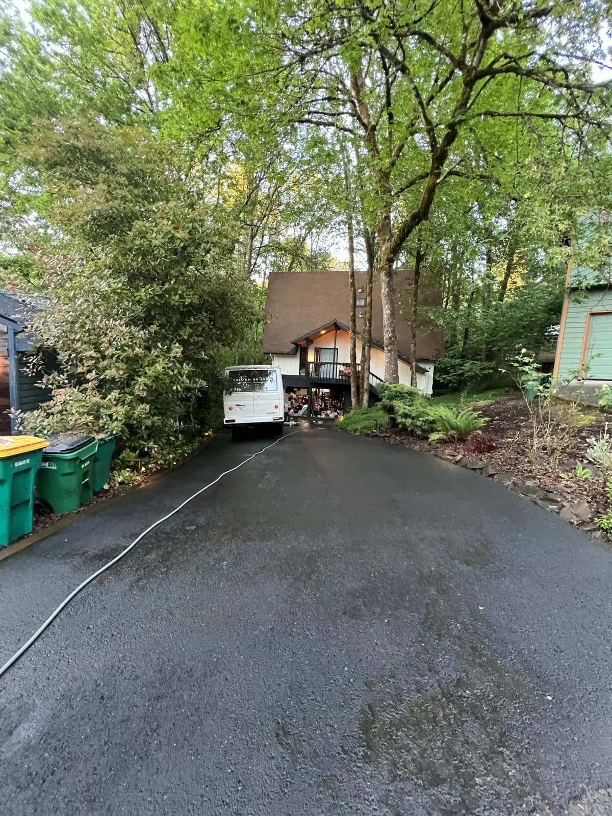 The same driveway rinsed clean and dark with water, looking down toward the street