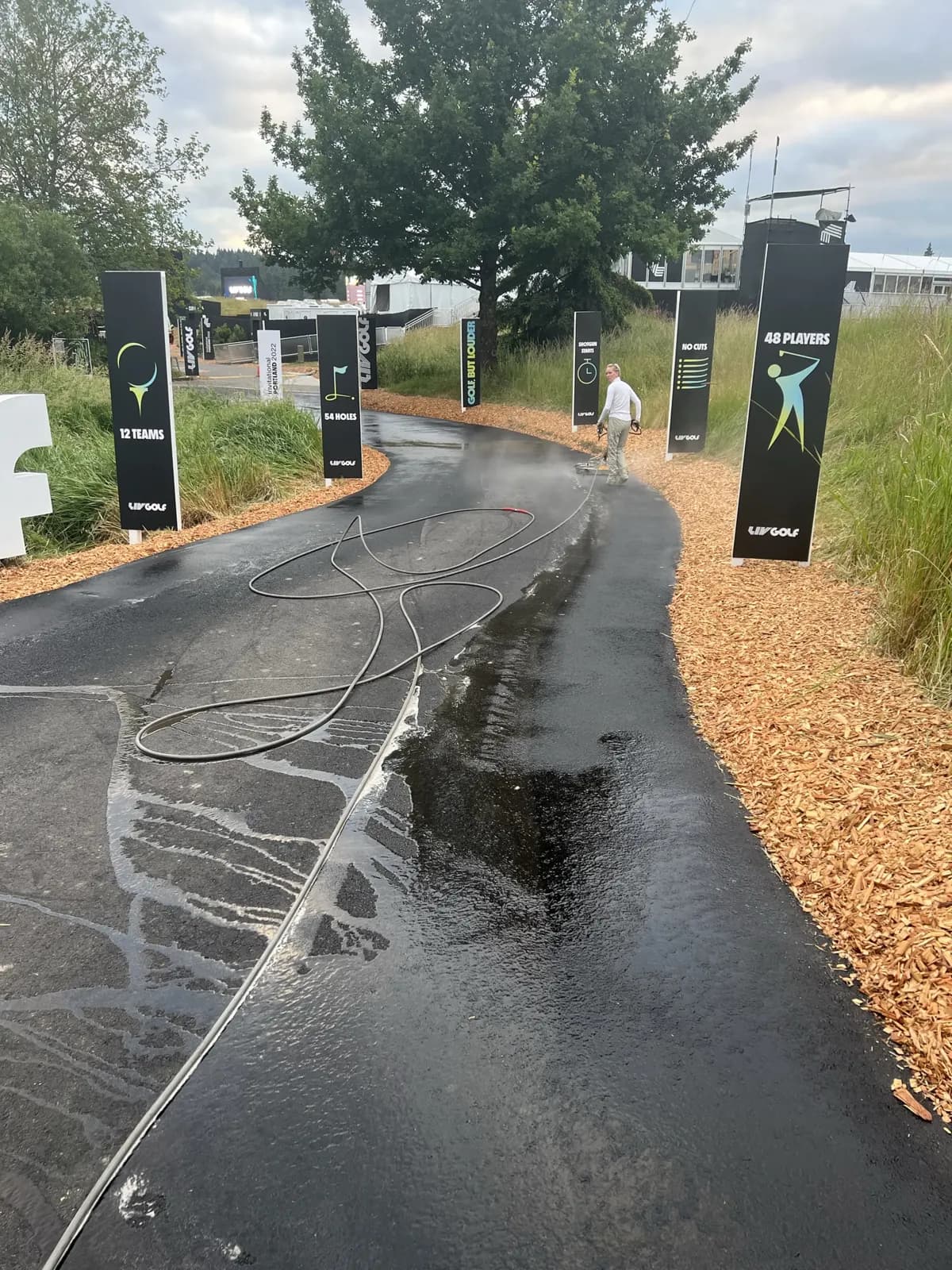 Asphalt walkway lined with event signage being rinsed down