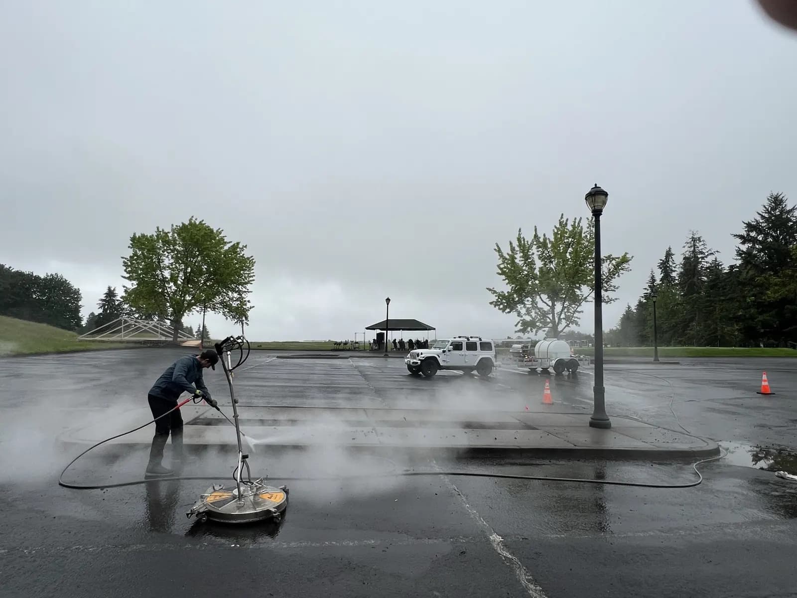 Wide view of a parking lot with a technician surface cleaning under low clouds
